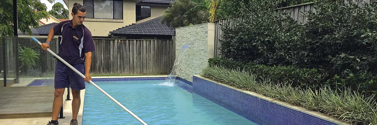technicien d'entretien de piscine nettoyant une piscine avec une épuisette