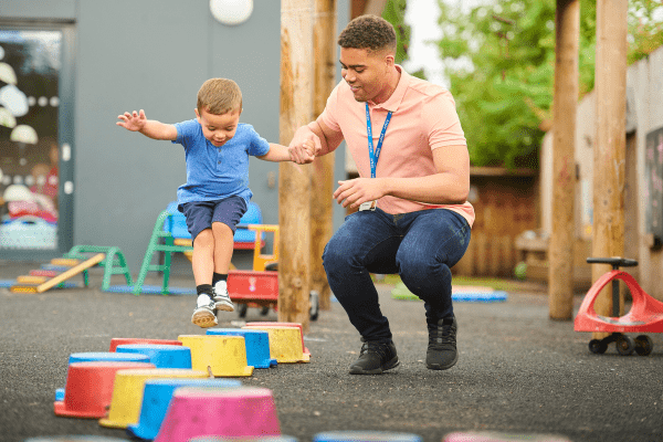 Accompagnant éducatif jouant avec un jeune enfant en extérieur