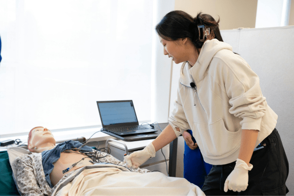 apprentie aide soignante qui s'entraine sur un mannequin