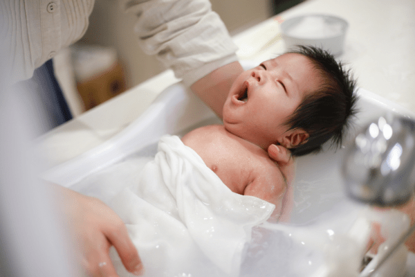 auxiliaire de puériculture donnant un bain à un nouveau né