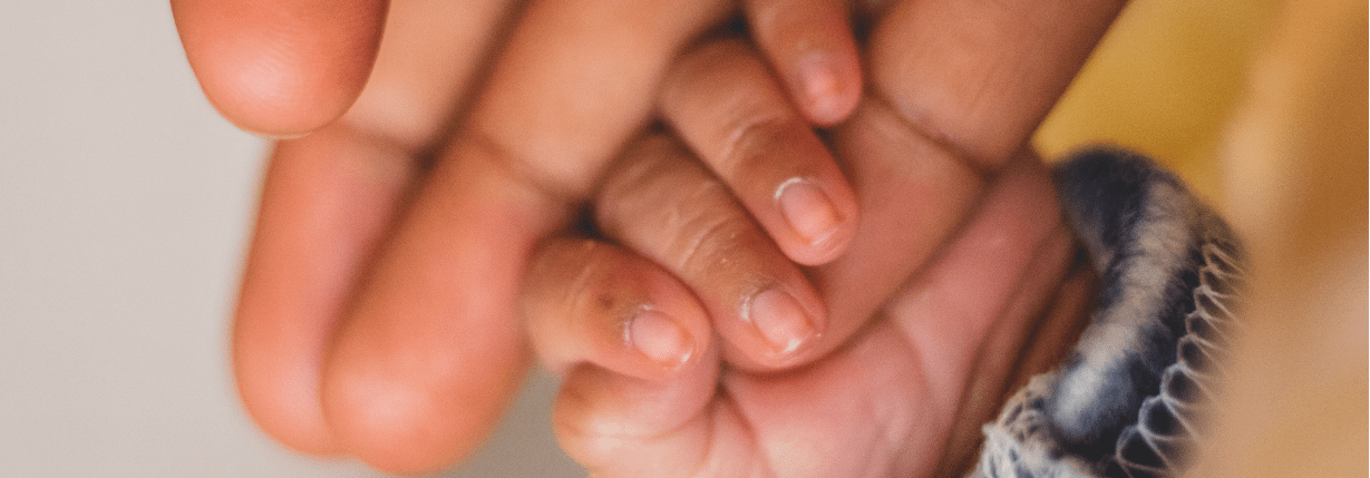 main de bébé dans la main d'une auxiliaire de puériculture