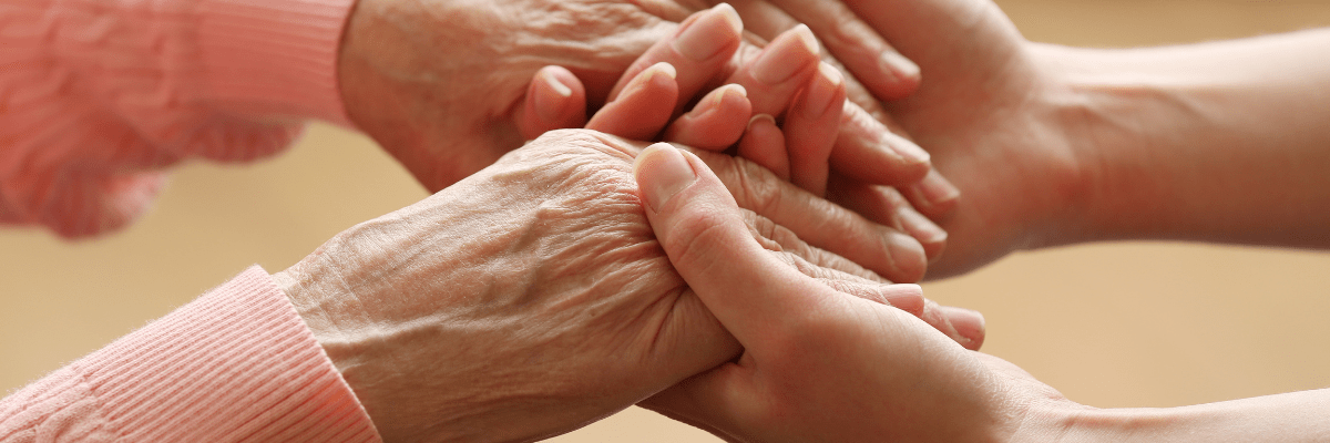 personne prenant les mains d'une personne âgée