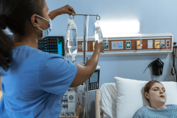 infirmière en train de vérifier la perfusion d'une patiente alitée