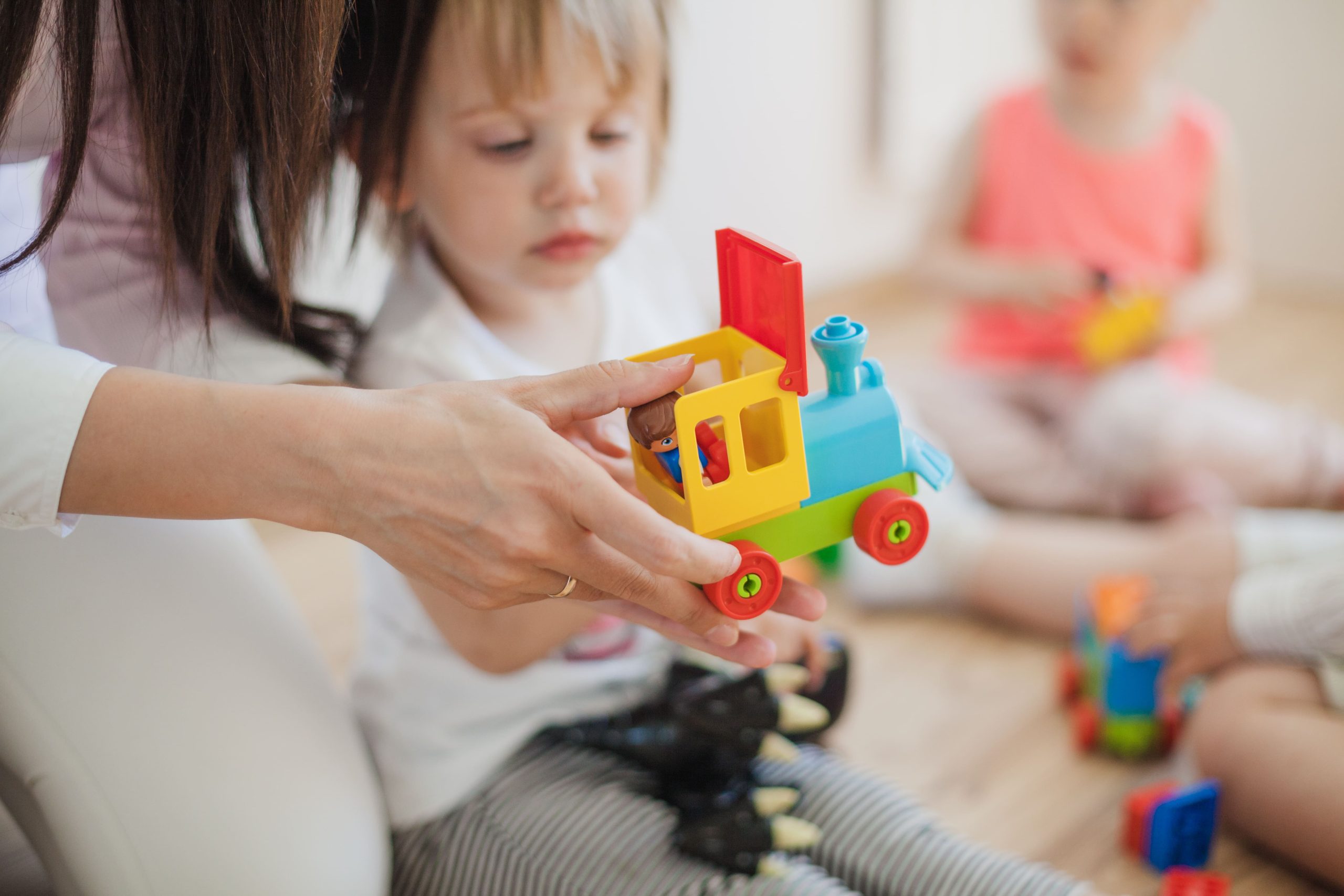 accompagnant éducatif donnant un jouet à un enfant dans une crèche